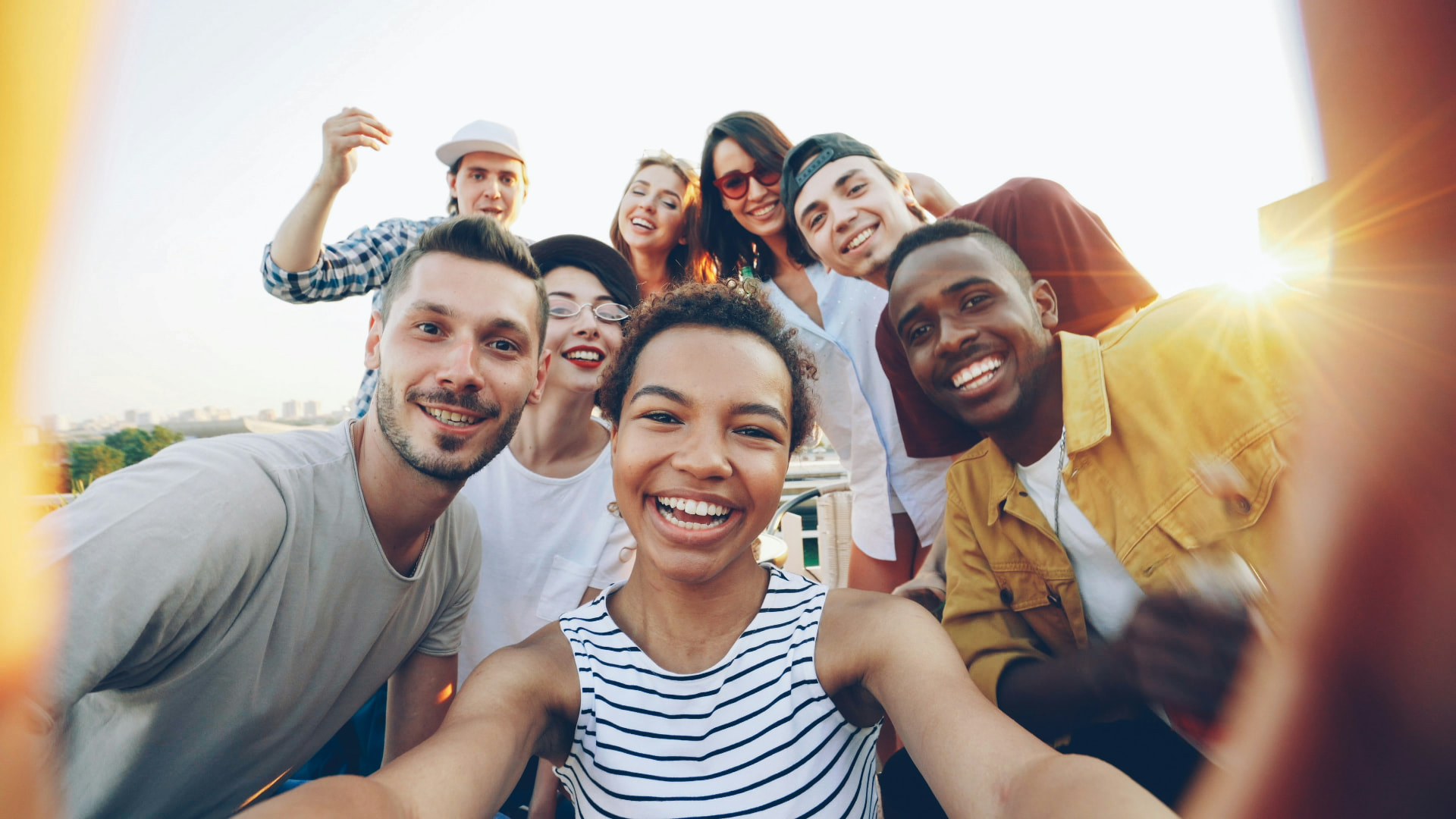 A group of friends laughing together outdoors in golden evening light